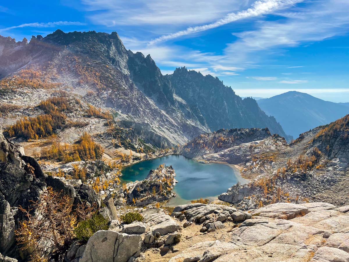 Mountainous landscape with a lake surrounded by rocky terrain and autumn-colored trees.