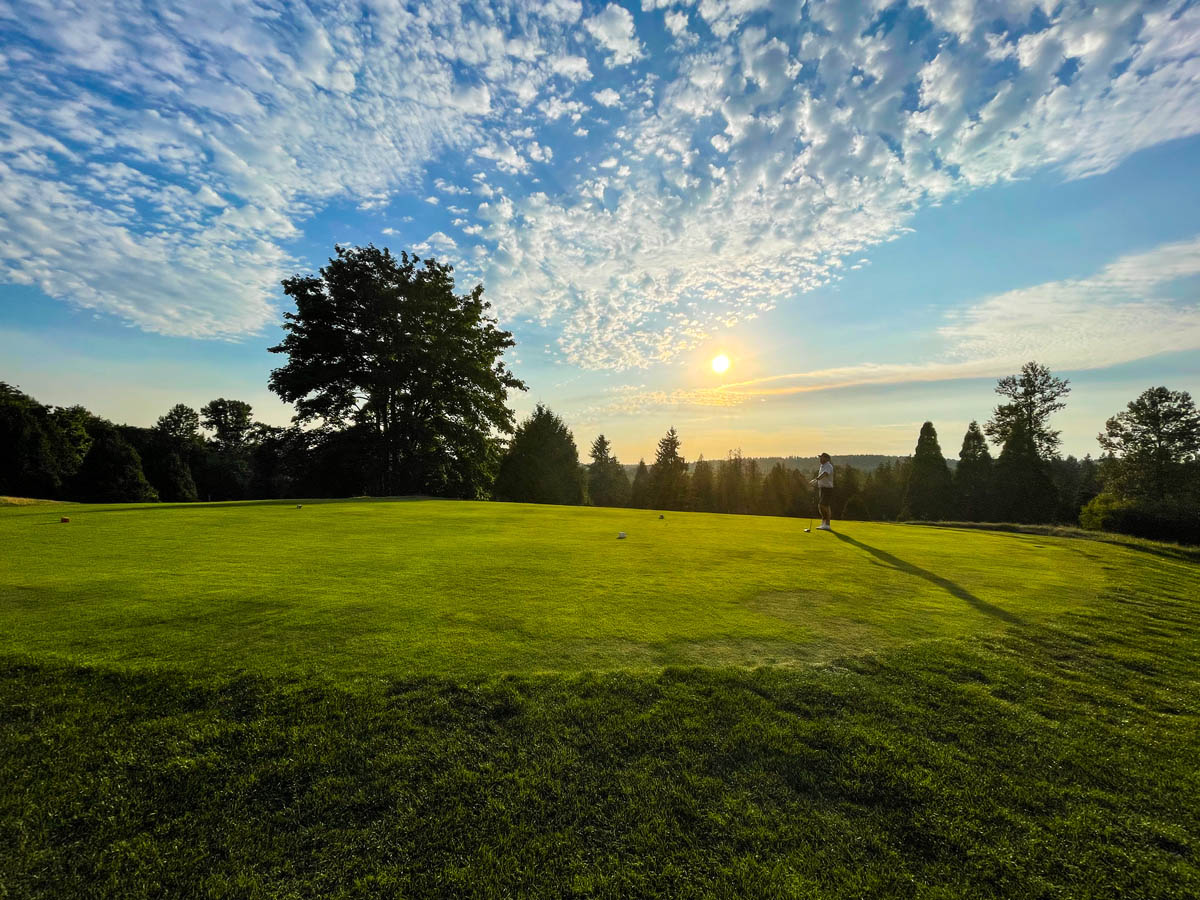 Golf course with trees and a sunset sky