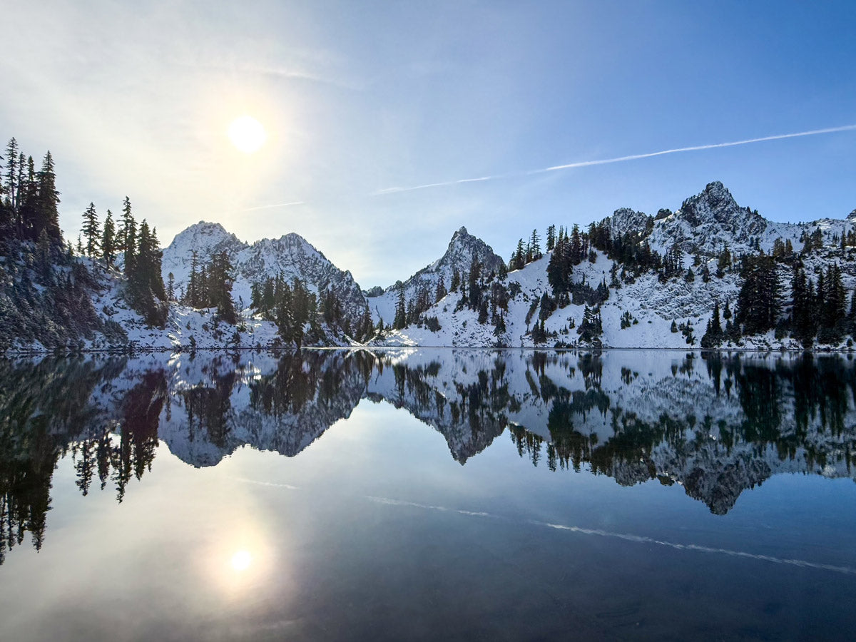 Mountain landscape with reflection in a lake under a clear blue sky.